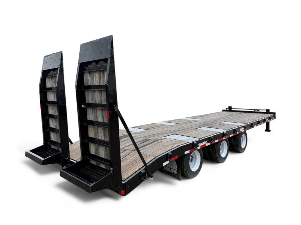 A black, triple-axle flatbed trailer with wooden deck and two raised loading ramps at the rear, shown on a white background.