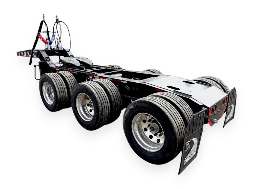 A heavy-duty truck tractor chassis with six wheels, exposed frame, and large mudflaps, photographed on a white background. No cab or trailer attached.
